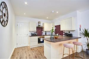 a kitchen with white cabinets and a counter with stools at Stunning 2 bed Apartment - Central Location in Leeds