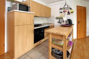 uma cozinha com armários de madeira, uma mesa e um micro-ondas em Apartment captain's cabin, Dornumersiel em Dornumersiel