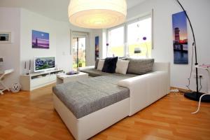 uma sala de estar com um sofá branco e uma televisão em Apartment captain's cabin, Dornumersiel em Dornumersiel