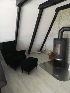 Una sala de estar con chimenea y una silla. en Ferienhaus Fynnhütte, en Schwarzenborn 16 fotos más