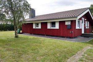 ein rotes Haus mit einem grünen Hof in der Unterkunft Holiday home Hunning in Hünning