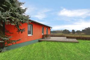 una casa roja con terraza y patio verde en Holiday homes Inselblick, Lohmen en Lohmen
