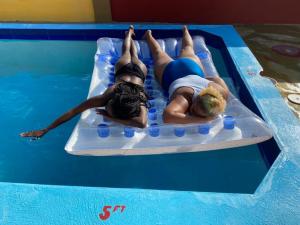 two people laying on a raft in a swimming pool at PARADISE VILLA SHAREd ONSITE PRIVATE POOL ONSITE GYM in Ocho Rios