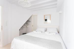 a white bedroom with a white bed and a staircase at aníko suites Chora in Mikonos