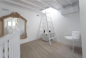 een witte kamer met een spiegel en een stoel bij aníko suites Chora in Mykonos-stad