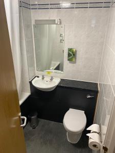 a white toilet sitting next to a sink in a bathroom at Purple Roomz Preston South in Preston