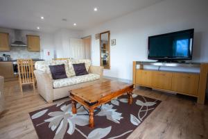 a living room with a coffee table and a flat screen tv at Denecroft apartments in Lynemouth