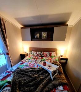 5 Geranium, Holiday Home in Oakdene Forest Park في فيرنداون: غرفة نوم مع سرير مع طاولة عليه
