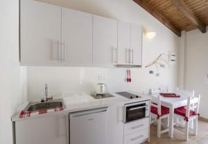 een witte keuken met een wastafel en een tafel bij Filoxenia Kirki Apartments by CorfuEscapes in Benitses