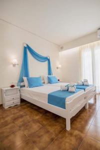 a bedroom with two large beds with blue curtains at Filoxenia Kirki Apartments by CorfuEscapes in Benitses