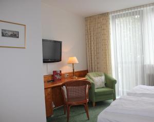 una camera d'albergo con scrivania, sedia e TV di Hotel Kurpfalzstuben a Mannheim Altre 32 foto