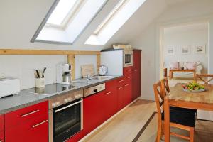 a kitchen with red cabinets and a wooden table at Gutshaus Zicker in Garz in Garz-Rügen