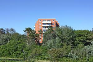 un edificio naranja en la cima de una colina con árboles en Apartment, St Peter-Ording, en Sankt Peter-Ording