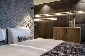 a bedroom with a white bed and a brown wall at Wellness- & Sporthotel Jagdhof in Röhrnbach