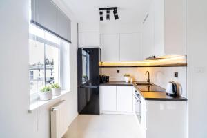 a white kitchen with a sink and a window at Park View Apartment przy plaży in Iława
