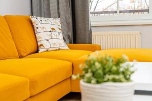 żółtą kanapę w salonie z rośliną w obiekcie Park View - przy plaży, parking, TV55" z Netflix i Max w Iławie
