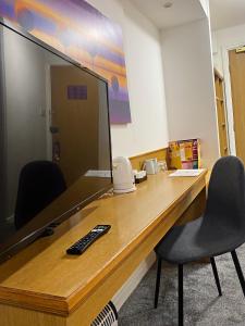 a desk with a monitor and a chair in front of it at Purple Roomz Preston South in Preston