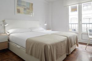 1 dormitorio blanco con 1 cama y 2 ventanas en Always Easy I Larroca, en San Sebastián