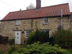 an old stone house with a red roof at Pass the Keys Scampton Cottage in Lincoln