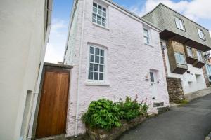 a white brick house with a wooden door at Rose Cottage - Kingsand in Kingsand