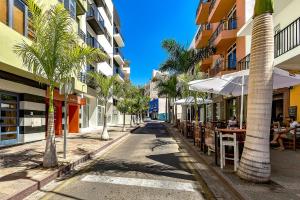 an empty street with palm trees and tables and buildings at Luxury Penthouse sea view, Los Cristianos in Los Cristianos