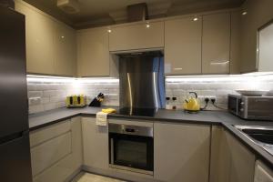 a kitchen with white cabinets and a stove top oven at Bournemouth Reef Apartment in Bournemouth