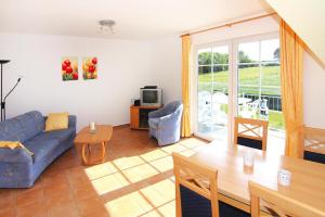 ein Wohnzimmer mit einem blauen Sofa und einem Tisch in der Unterkunft Ferienanlage Schuldt, Behrensdorf in Behrensdorf