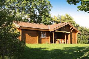 eine Blockhütte mit einer Veranda und Stühlen im Hof in der Unterkunft Ferienhäuser Lauterdörfle, Hayingen in Hayingen
