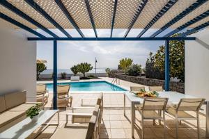 a patio with a table and chairs and a swimming pool at Lanzarote Villa The One in Playa Blanca
