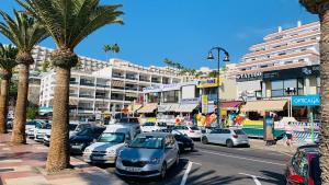 uma movimentada rua da cidade com carros e palmeiras em Playa la Arena Apartment by the Beach em Puerto de Santiago