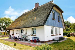 een klein wit huis met een rieten dak bij Apartment, Wieck am Darss in Wieck