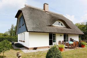 a thatch roofed house with a patio in a yard at Apartment, Wieck am Darss in Wieck