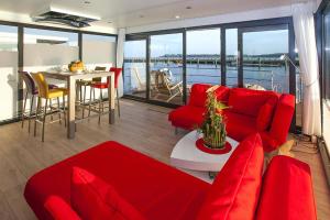 sala de estar con muebles de color rojo y vistas al agua en Houseboat Floating Houses Blue Active, Ribnitz-Damgarten, en Ribnitz-Damgarten