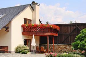 een wit huis met een balkon met rode bloemen bij Holiday complex Landlust M hlental in Oberwürschnitz