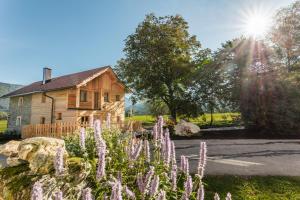 a wooden house with purple flowers in front of it at Ferienhaus Spitzenhof - Urlaub am Bauernhof in Mooslandl