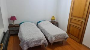 two beds in a room with a table and a lamp at Le bonhomme proche de Kaysersberg et du lac blanc in Le Bonhomme