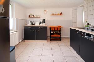uma cozinha com armários pretos e piso em azulejo em Holiday home shore view, Teupitz em Teupitz