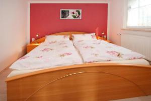 uma cama de madeira com almofadas brancas e uma parede vermelha em Holiday home shore view, Teupitz em Teupitz