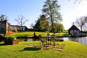 a table and chairs in the grass next to a pond at Holiday Farm by Red River with Indoor Pool in Pfaffenhoffen