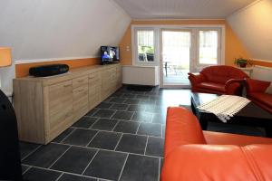 uma sala de estar com mobiliário laranja e uma televisão em Holiday home Stork's Nest 2, Falkensee em Falkensee