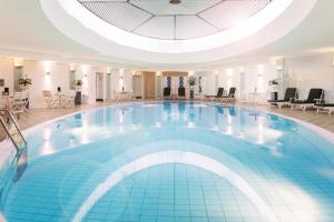 a large swimming pool in a hotel with a domed ceiling at Hotel Bristol Berlin in Berlin