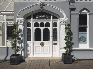 une porte blanche d'un bâtiment avec deux plantes en pot dans l'établissement Oaklands Guest House, à Weymouth