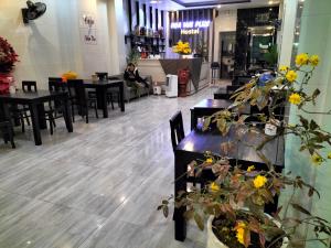 a restaurant with tables and chairs and a person sitting at a counter at HOA MAI Plus Hostel in Dong Hoi