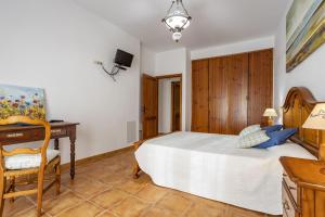 a bedroom with a bed and a desk and a chair at Finca Coqueta in El Port de la Selva