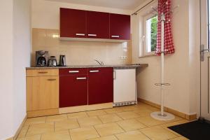 a kitchen with red cabinets and a tile floor at Bungalow summer house, Parchim in Parchim