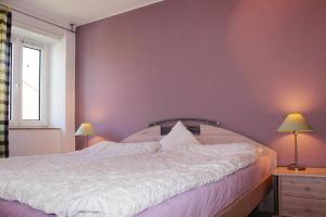 a bedroom with a white bed with a purple wall at Terraced house, St Peter-Ording in Westereck