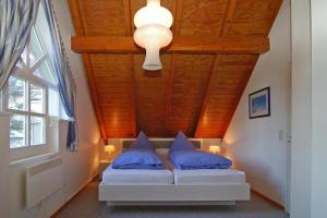 Una cama con almohadas azules en una habitación con techo de madera. en Holiday home Fischer Sien Huus, Steinhude, en Steinhude