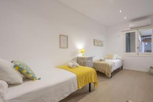 a white bedroom with two beds and a yellow blanket at House Can Toni in Port d'Alcudia +29 photos