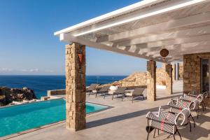 a patio with chairs and a swimming pool with the ocean at Anarina Villas & Suites Elia Beach in Mýkonos City