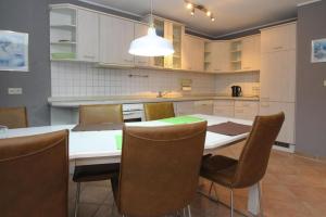 Apartment, Malchow في مالتشو: مطبخ مع طاولة وكراسي ومطبخ مع دواليب بيضاء